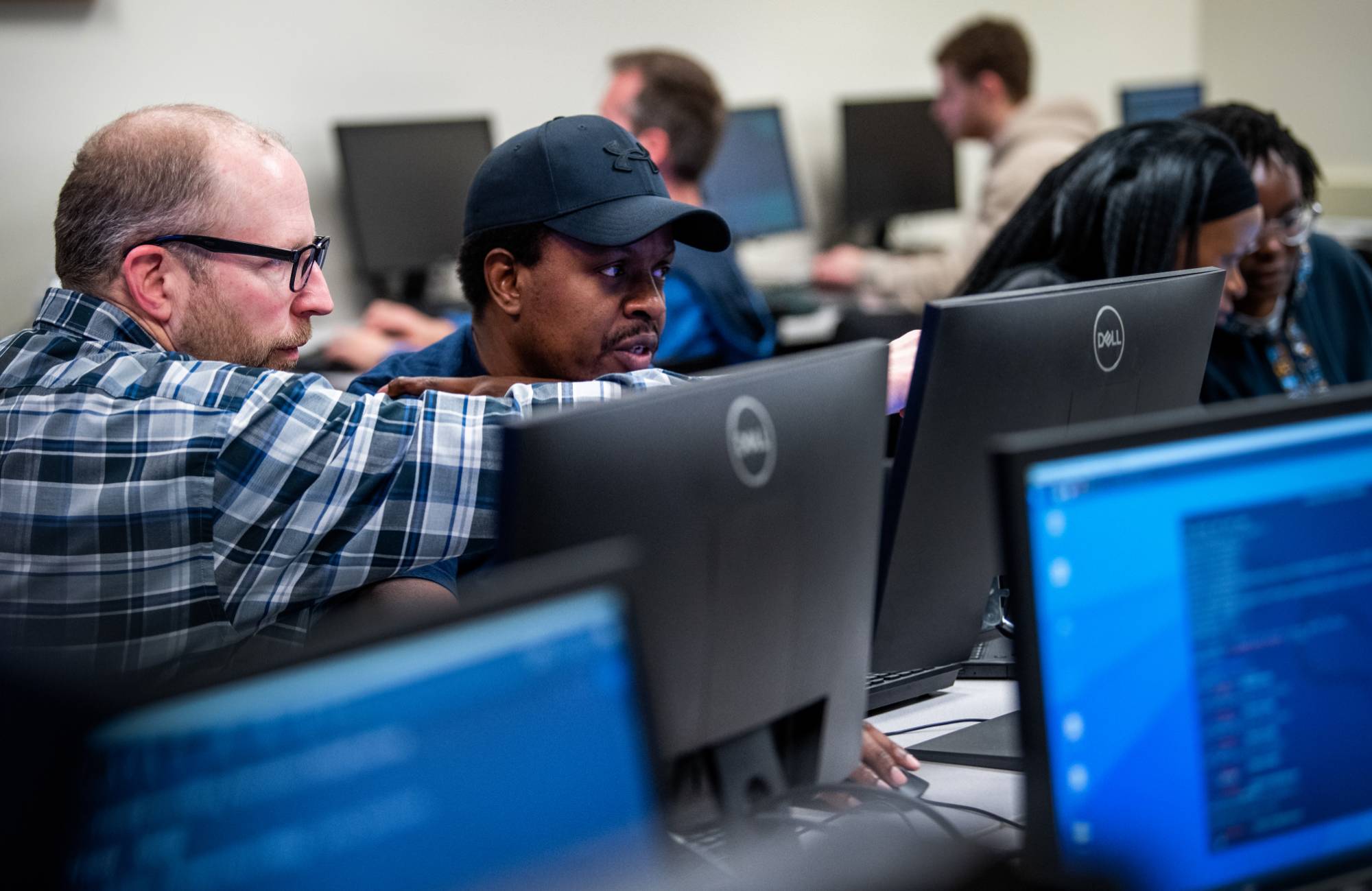 Students and faculty working in the Cyber Range space together.